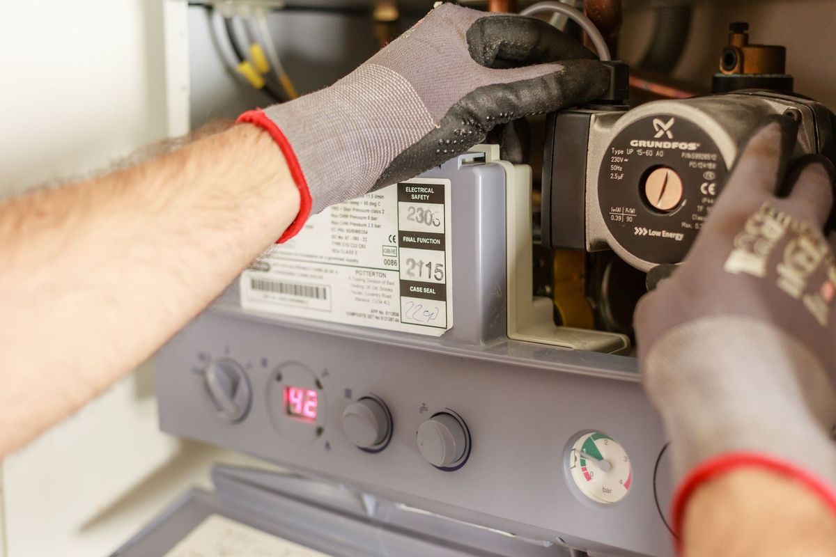 Technicien inspectant un appareil électrique avec gants et outils Technicien inspectant un appareil électrique avec gants et outils