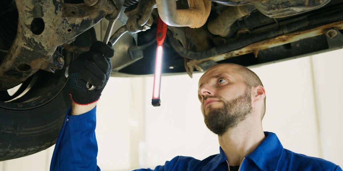 Mécanicien inspectant sous un véhicule avec des outils