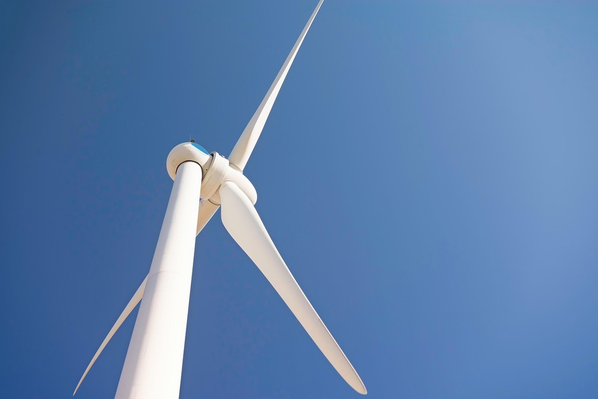 Éolienne blanche à trois pales vue de bas, ciel bleu Éolienne blanche à trois pales vue de bas, ciel bleu