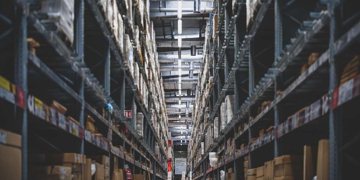 Allée d'entrepôt avec des étagères métalliques pleines de cartons