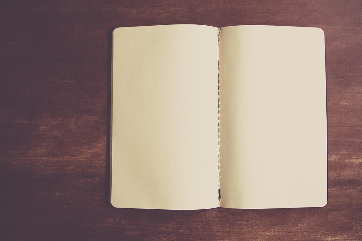 Carnet ouvert sur une table en bois. Pages blanches, sans écriture