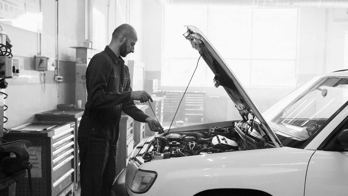 Mécanicien travaille sur le moteur d'une voiture dans un atelier Mécanicien travaille sur le moteur d'une voiture dans un atelier