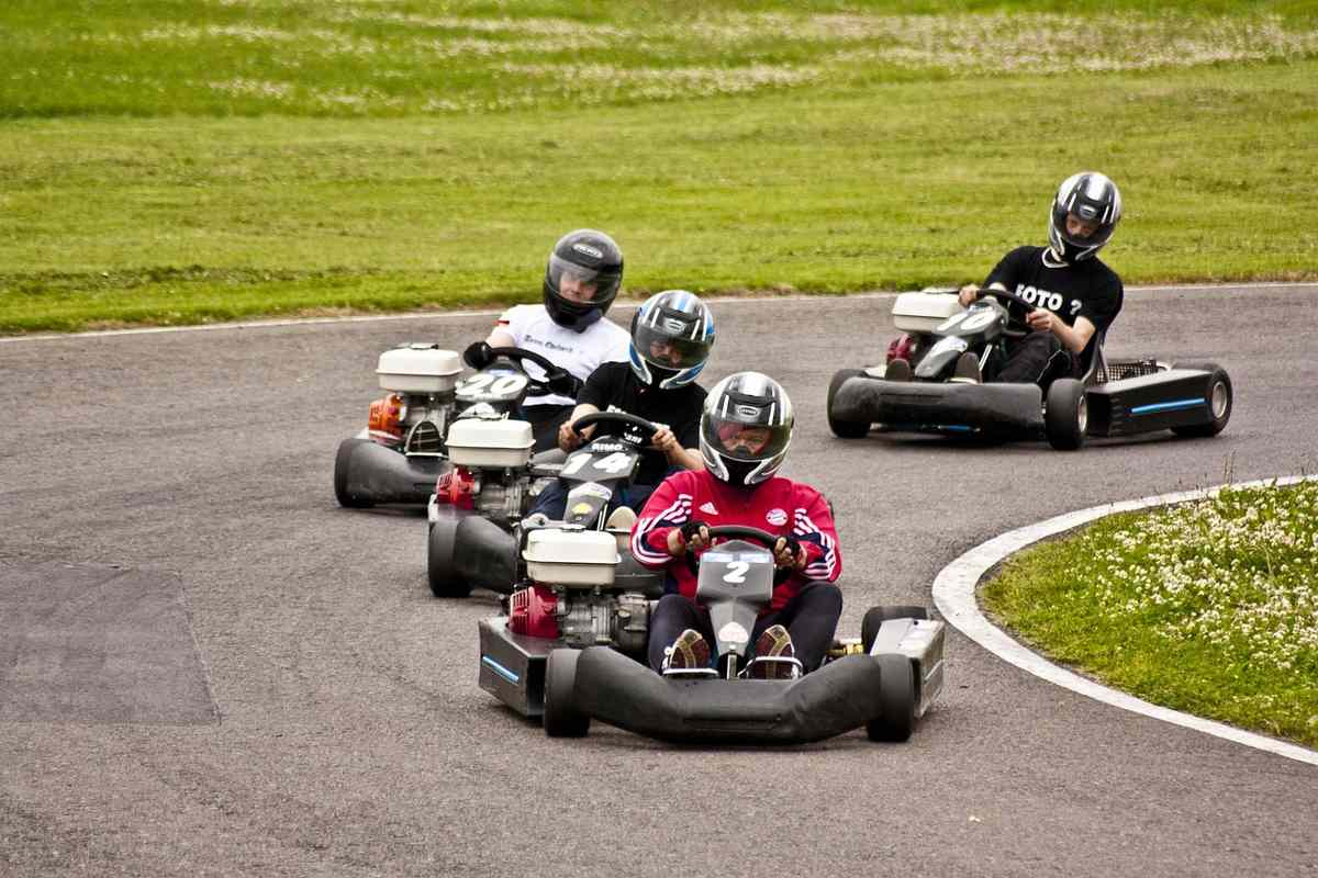 Quatre personnes pilotent des karts sur un virage de circuit Quatre personnes pilotent des karts sur un virage de circuit