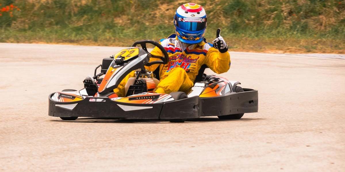 Un pilote en karting sur piste, portant casque coloré et souriant
